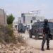 Members of the Israeli security forces stand guard near a Palestinian house, which was besieged by Israeli settlers, in Qusra