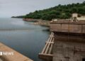 The Kariba dam seen from one of its ridges, overlooking the reservoir and green landscape in the distance