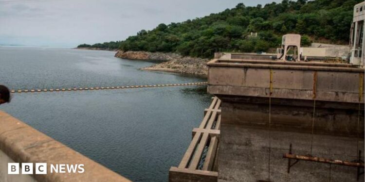 The Kariba dam seen from one of its ridges, overlooking the reservoir and green landscape in the distance