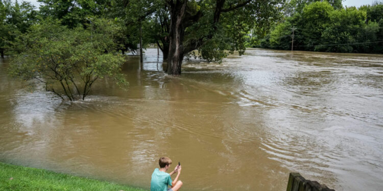 Chace Dexter films the swollen White River due to flooding after days of heavy rain in Noblesville