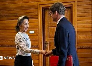 Former Myanmar president Aung San Suu Kyi shakes hands with an official from the International Committee of the Red Cross