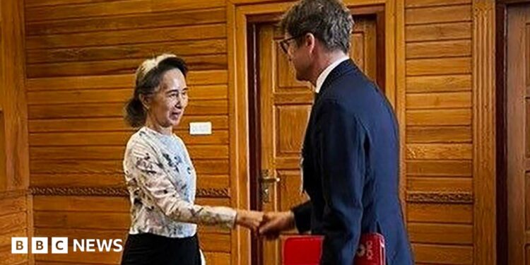 Former Myanmar president Aung San Suu Kyi shakes hands with an official from the International Committee of the Red Cross