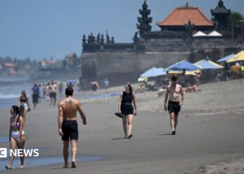 Tourists walk on a beach in Bali