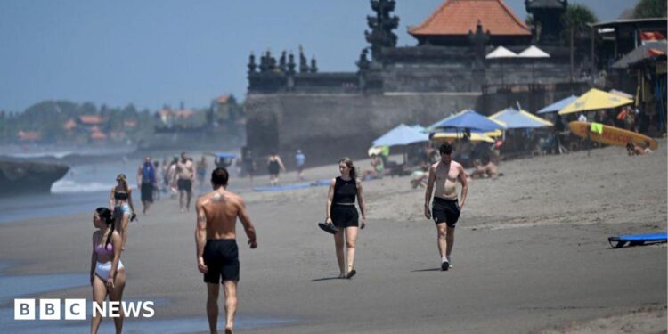 Tourists walk on a beach in Bali