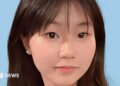 Close-up of a young Chinese girl smiling at the camera, against a blue background