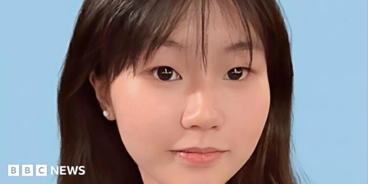 Close-up of a young Chinese girl smiling at the camera, against a blue background