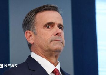 John Ratcliffe seen in a navy suit, with a red tie.