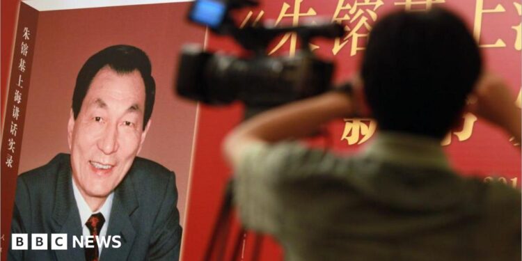 Poster of book with former Chinese premier Zhu Rongji on the cover and a blurred image of a man and a TV camera in the foreground