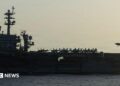Side view of USS Abraham Lincoln as a small jet lands on it
