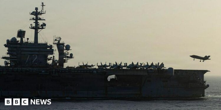 Side view of USS Abraham Lincoln as a small jet lands on it