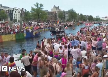 Revellers line Amsterdam canal to watch the annual Pride boat parade