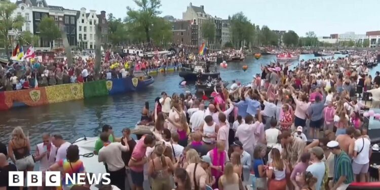 Revellers line Amsterdam canal to watch the annual Pride boat parade