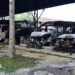 Five burned out vehicles are lined up under a tin roof structure