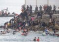 Dozens of migrants walking on a coastal path