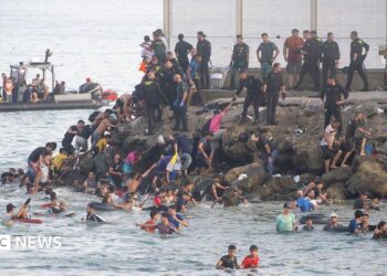 Dozens of migrants walking on a coastal path