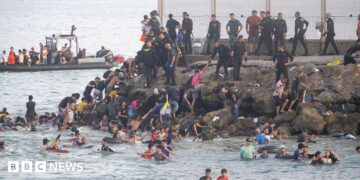 Dozens of migrants walking on a coastal path