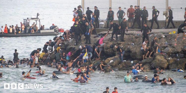 Dozens of migrants walking on a coastal path