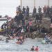 Dozens of migrants walking on a coastal path