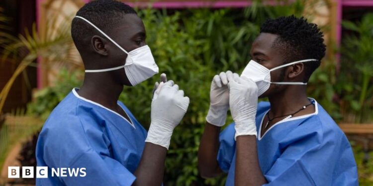 Two men wearing protective gear face each other while adjusting their masks