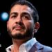 Abdul El-Sayed on stage wearing an open necked white shirt and blue suit jacked, at an election night watch party at The Majestic Theatre in Detroit