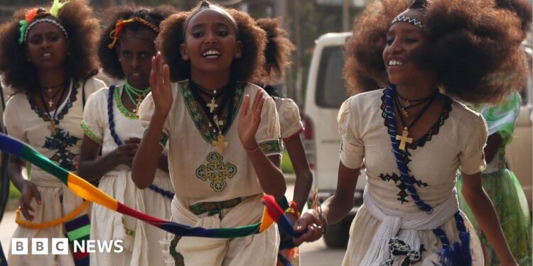 Orthodox Christian women clap as they walk down in traditional white outfits with silver cross necklaces in Mekelle in Ethiopia - archive shot