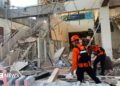 Emergency workers look through the rubble at Lauren Say port in Maumere