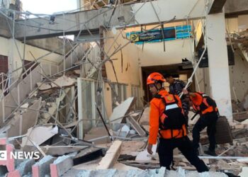Emergency workers look through the rubble at Lauren Say port in Maumere