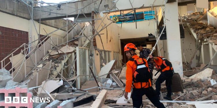Emergency workers look through the rubble at Lauren Say port in Maumere