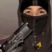 A teenager wearing a black balaclava and hoodie holding up a handgun, with his gloved hand on the trigger