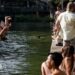A man jumps into the water as people gather along the banks of the Canal Saint-Martin in Paris, France. Photo: 29 July 2026