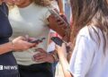 Teenage girls use social media on their smartphones in France. Photo: July 2026