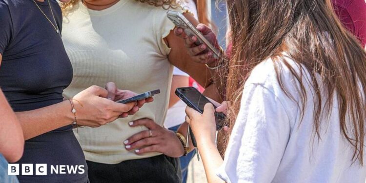 Teenage girls use social media on their smartphones in France. Photo: July 2026