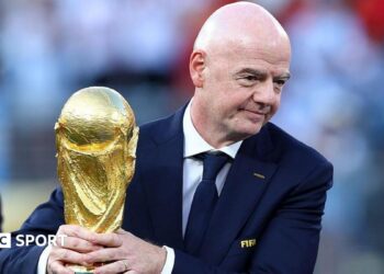 Gianni Infantino with his hands around the men's World Cup trophy