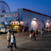 People walk along the Ocean City, New Jersey, boardwalk as the Ferris wheel rises in the background