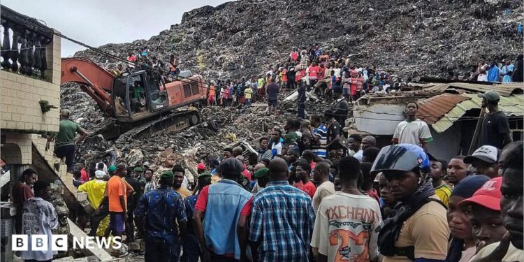 Rescuers use an excavator to comb through a mountain of scattered rubbish at a major waste site in Conakry, Guinea, as local residents gather nearby. Photo: 23 August 2026