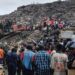 Rescuers use an excavator to comb through a mountain of scattered rubbish at a major waste site in Conakry, Guinea, as local residents gather nearby. Photo: 23 August 2026