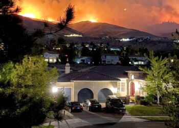 Flames burning in hills above a home