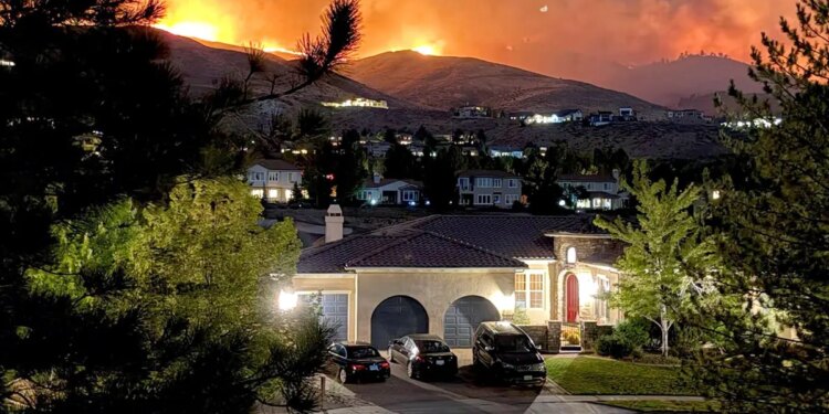 Flames burning in hills above a home
