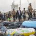 Rubber flotation rings sit on a beach in front of a line of arriving migrants in Ceuta.