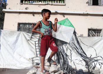 A Palestinian boy holds a kite at a displacement camp in Gaza City (23 August 2026)