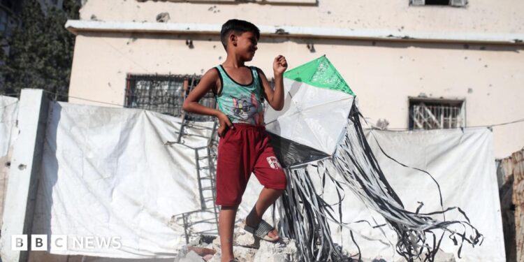 A Palestinian boy holds a kite at a displacement camp in Gaza City (23 August 2026)