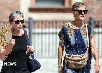 People drink water and use hand fans to protect themselves from the sun in Naples, southern Italy. Photo: 1 August 2026
