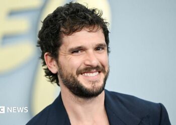 Kit Harrington seen smiling on the red carpet in a blue blazer on the red carpet in New York in May.