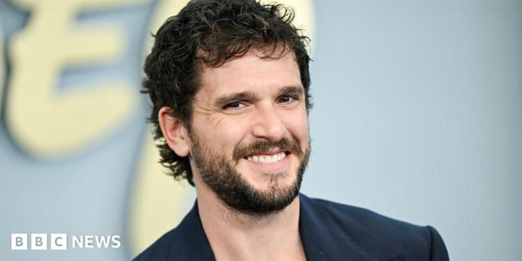 Kit Harrington seen smiling on the red carpet in a blue blazer on the red carpet in New York in May.