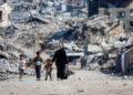 Palestinians walk past the rubble of residential buildings destroyed during the war, in Gaza