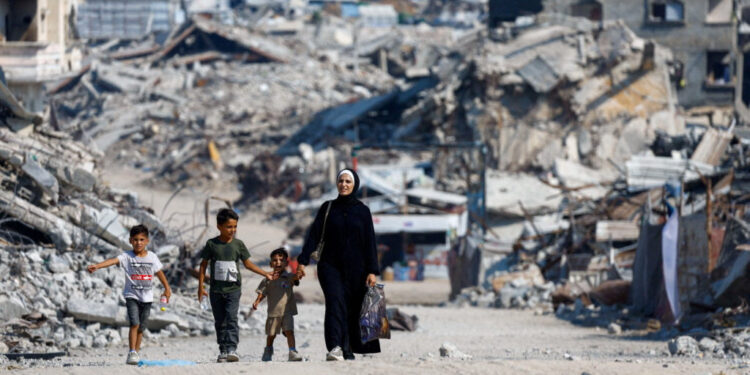 Palestinians walk past the rubble of residential buildings destroyed during the war, in Gaza