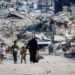 Palestinians walk past the rubble of residential buildings destroyed during the war, in Gaza