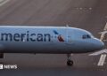 The front of an air plane with the American logo on a runway.
