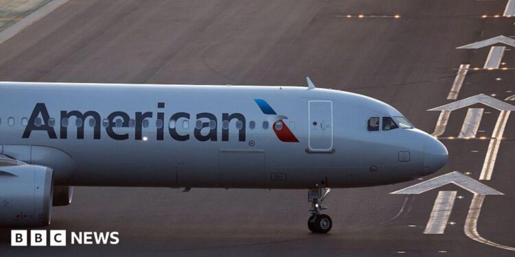 The front of an air plane with the American logo on a runway.