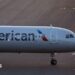 The front of an air plane with the American logo on a runway.